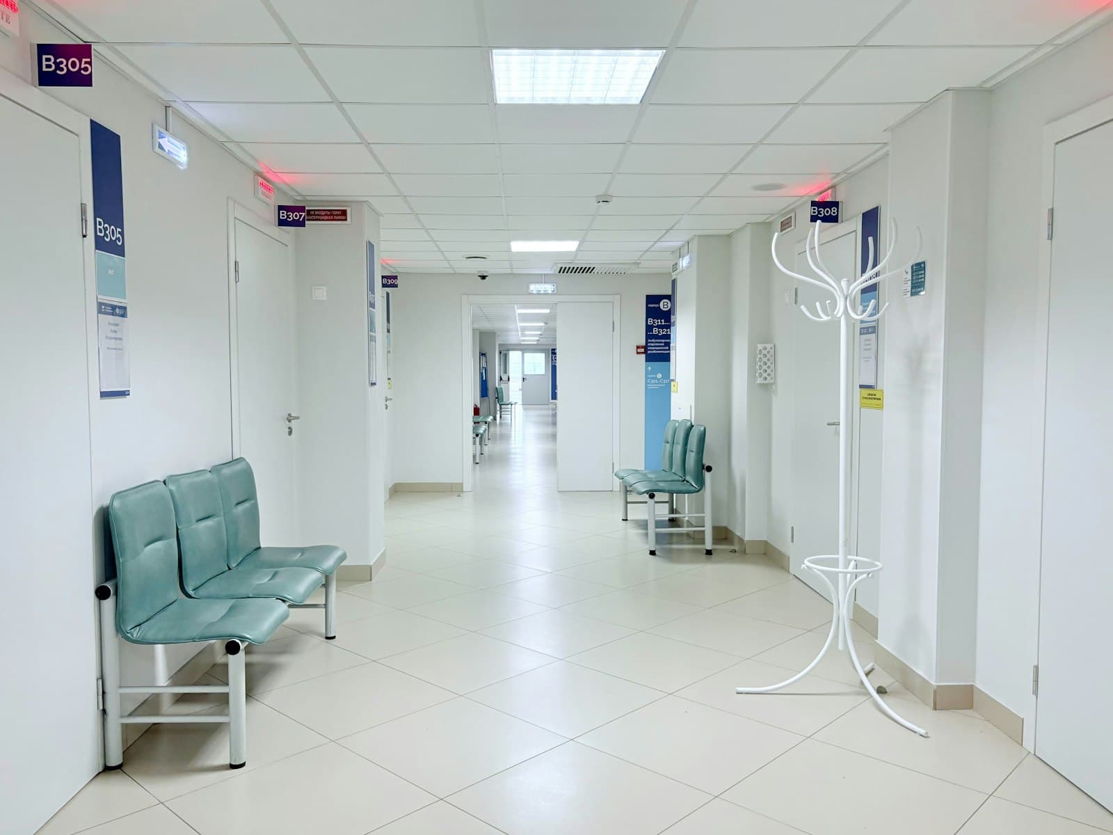 An empty hospital corridor with benches and doors