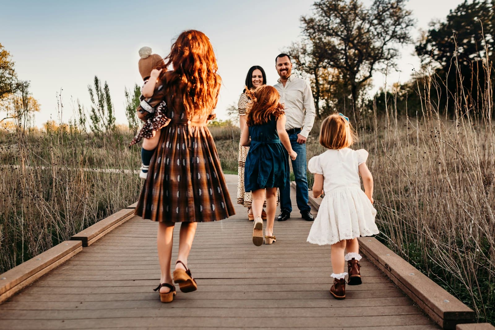 A family walking away along a boardwalk at golden hour